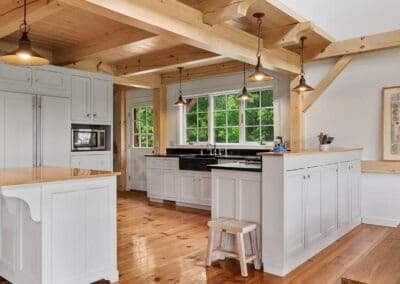 Old Chatham Barn Home featuring a white kitchen with wooden beams and wood floors.