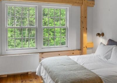 Old Chatham Barn Home with wood beams and a white bed in the bedroom.